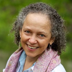 Elder woman smiling outdoors, discussing psychedelics and attunement.